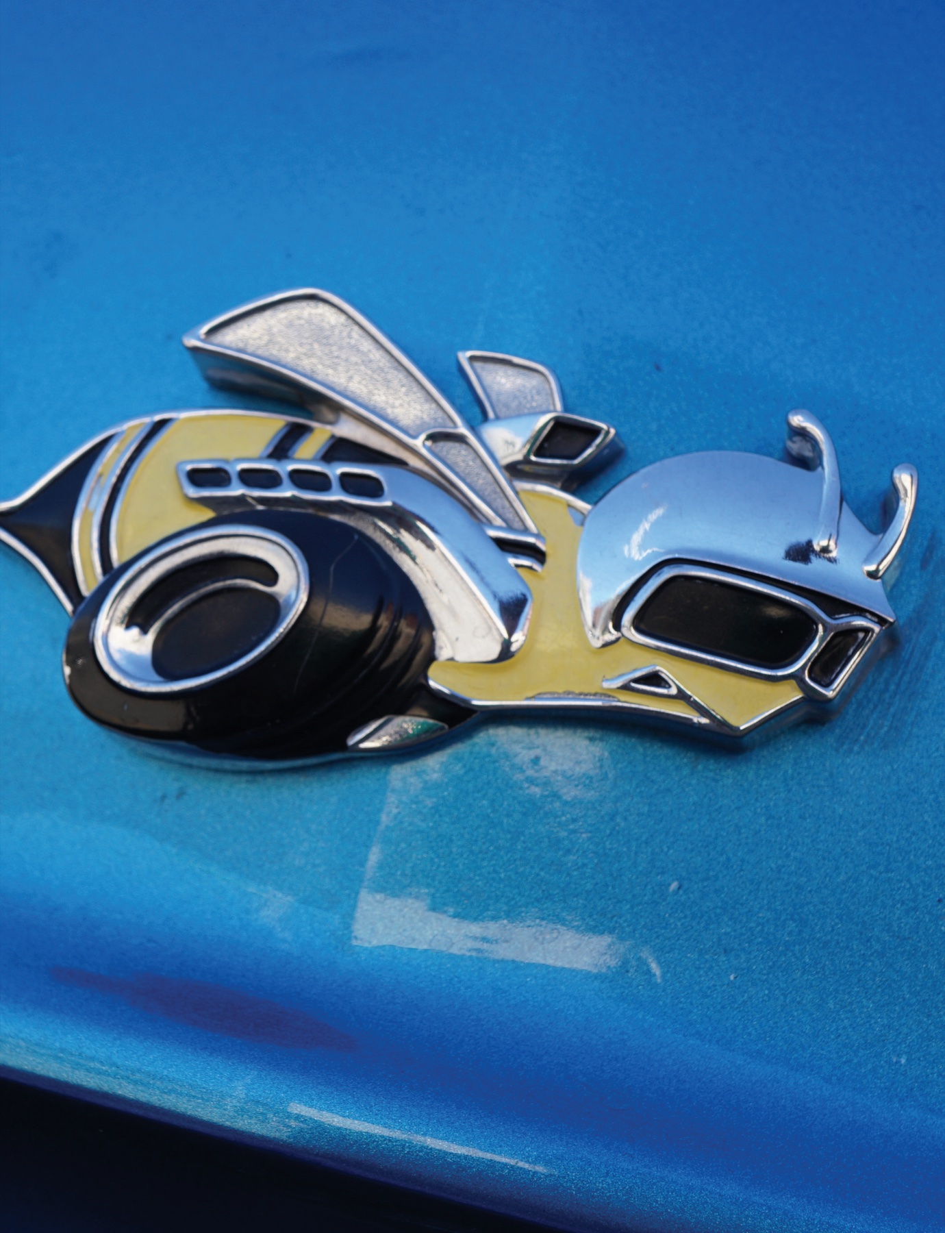 Chrome bee emblem on a blue car body